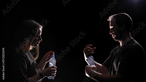 Young couple throw water bottles into the air and drink from them