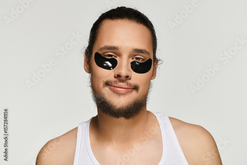 Φωτογραφία Handsome young bearded man enjoying self care routine with eye patches
