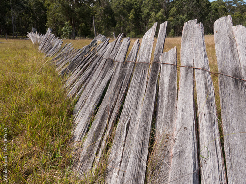Old paling fence falling down in a grass paddock