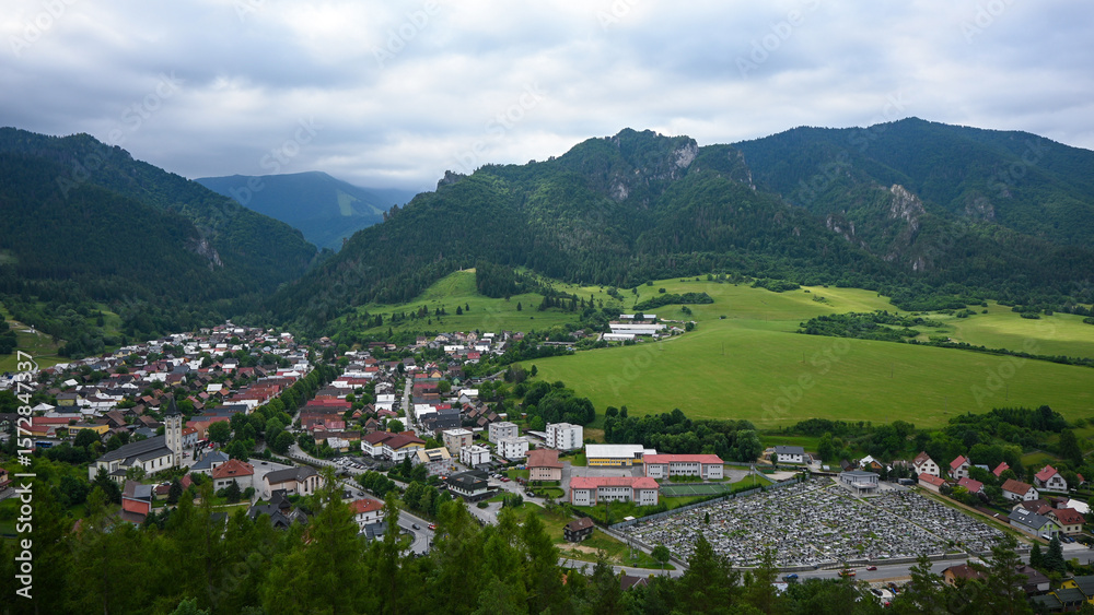 Fototapeta premium Breathtaking view of a charming european town nestled amidst rolling green hills and imposing mountains, creating a serene and idyllic scene