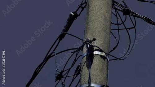 an electric pole with a dark sky and lightning in the background. some of the electrical components were destroyed and smoking due to the effects of the lightning.