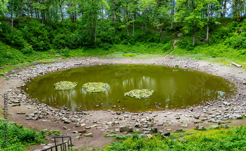 Scenic meteorite crater lake Kaali surrounded by forested terrain.