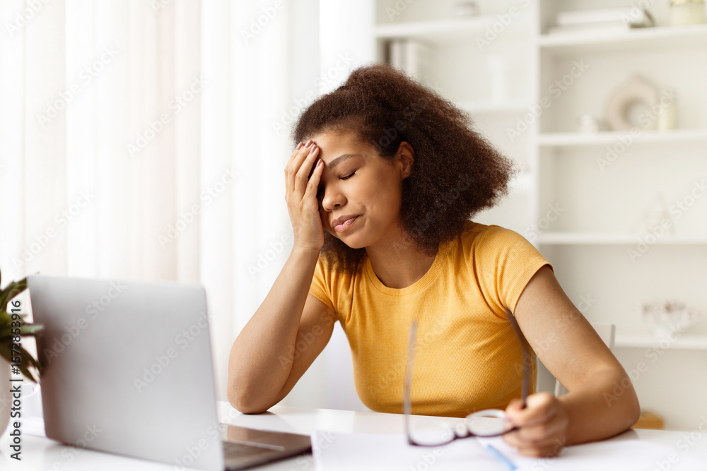 Frustrated young black woman with hand on face and holding glasses. Feeling tired or disappointed during online work or remote study from home desk, closeup Frustrated young black woman with hand on face and holding glasses. Feeling tired or disappointed during online work or remote study from home desk, closeup