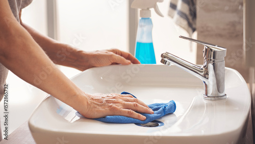 Hands of female cleaning lavatory sink