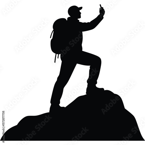A silhouette of a hiker with a backpack on a mountain taking a picture with a mobile phone device