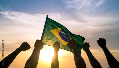 Silhouetted fists are raised in unity below a waving Brazilian flag against a vibrant sunset sky. This powerful image symbolizes patriotism, protest, and the spirit of the Brazilian people.