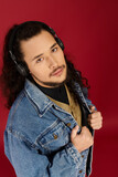 Handsome young bearded man wearing headphones strikes a confident pose against a vibrant backdrop