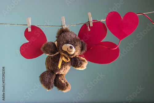 Foto Toy Teddy bear with papers hearts are suspended from the rope clothespins on a b