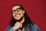 Handsome young bearded man smiling with confidence against a vibrant red background