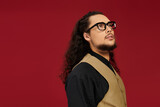 Handsome young man with beard showcasing style against vibrant red backdrop