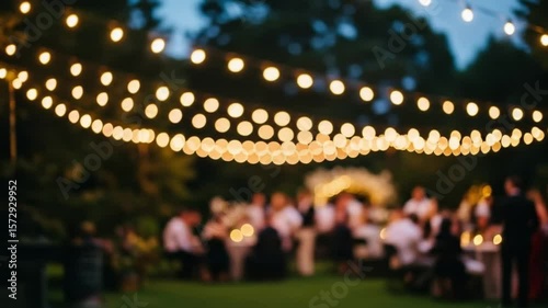 A blurry, slow panning shot of a festive garden party at night, with string lights overhead and people socializing, creating a dreamy ambiance.
