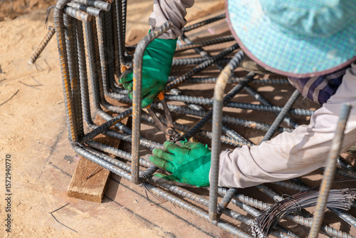 Workers are tying rebar with wire to prepare for foundation casting.