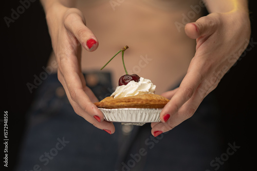 A captured moment of a person about to enjoy a cherry-topped pie, emphasizing emotions of joy and anticipation paired with a dark background to enhance the intimate atmosphere.