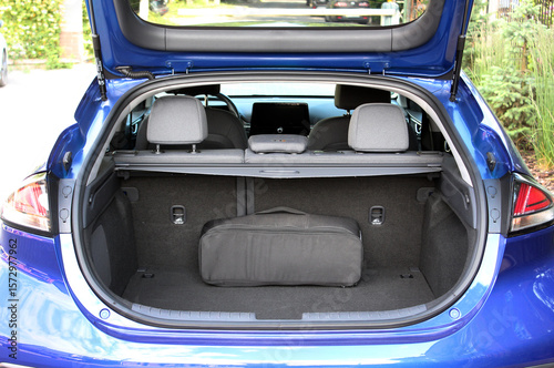 Clean, open empty trunk in blue car close up. Empty trunk of a modern blue car. Car boot is open. Modern electric car with open empty trunk. Open luggage carrier of vehicle close up.