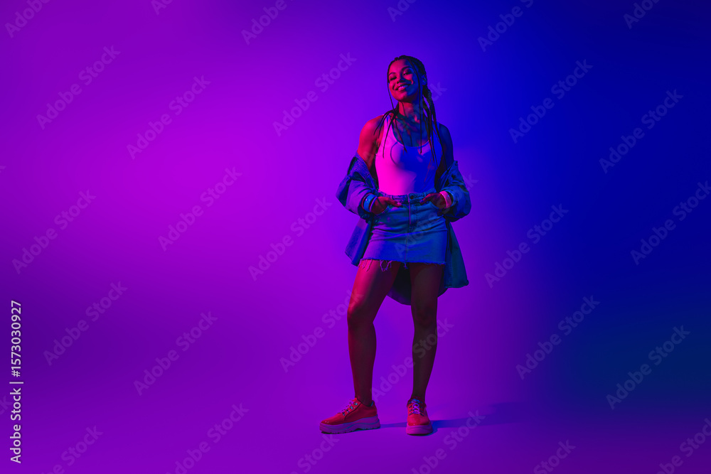 Stylish young woman in trendy outfit posing in vibrant neon lighting, purple background, embracing modern casual fashion. Stylish young woman in trendy outfit posing in vibrant neon lighting, purple background, embracing modern casual fashion.