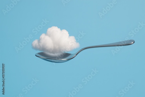 Fluffy Cumulus Cloud Resting on Silver Spoon Against Sky Blue Background