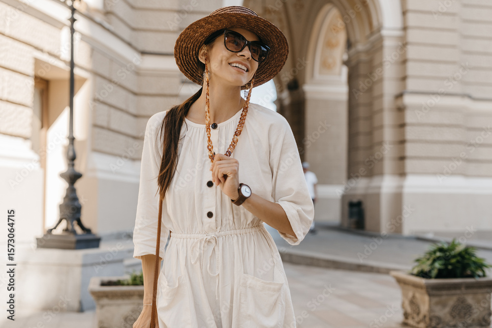 Fototapeta premium beautiful woman walking in street on vacation dressed in white summer fashion dress