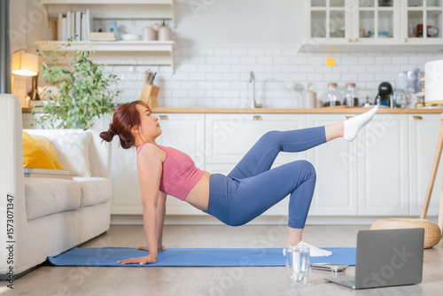 Young asian athletic woman doing a home workout on an exercise mat  practicing yoga and stretching exercises like triangle pose and plow pose for spine flexibility and strength