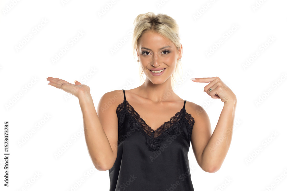 Fototapeta premium Blonde woman in black top smiling and presenting with open palm, studio shot on white background