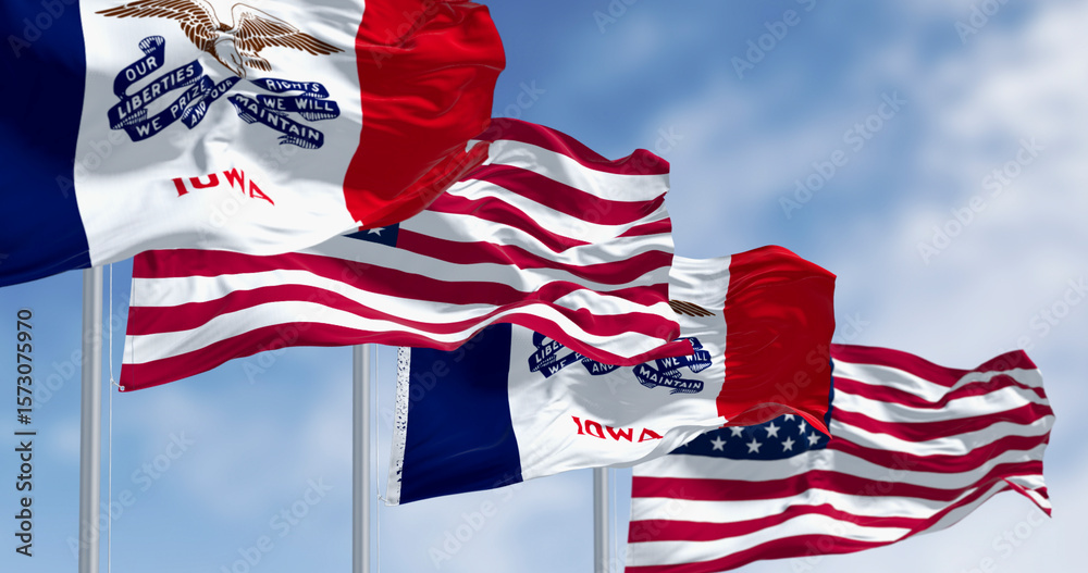 Naklejka premium Iowa state flag waving in the wind with the US flag on a clear day