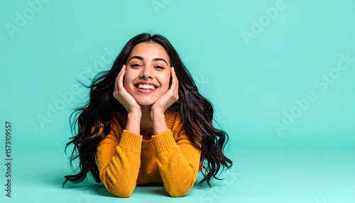 Smiling Young Woman with Long Wavy Hair in Yellow Sweater Against Mint Green Background