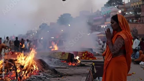 Woman prays, cremation fire, city ghats, India