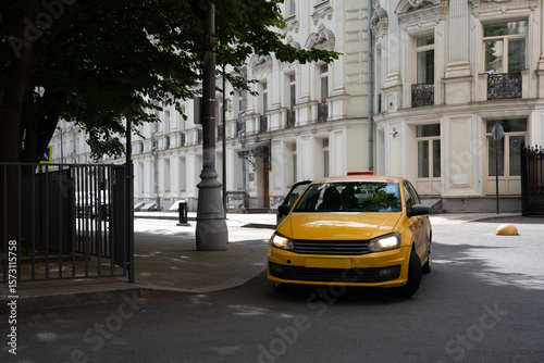A bright yellow taxi cab is making a turn at a busy urban intersection in the city