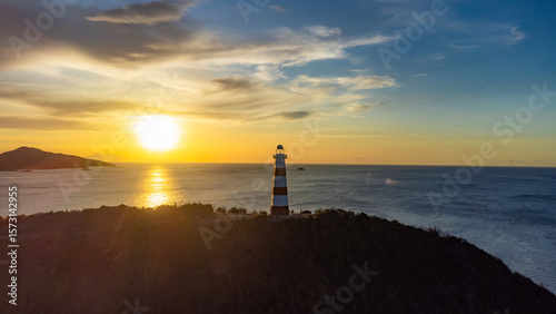Lighthouse is on a hill overlooking the ocean
