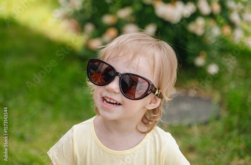 Funny little girl in summer with sunglasses, cheerful childhood moment