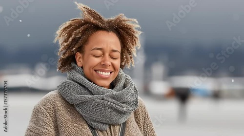 African American woman with curly hair, wearing a cozy sweater and scarf, joyfully embracing winter snowfall outdoors, expressing happiness and freedom in a serene environment
