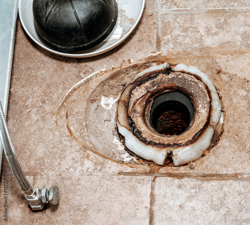 Close-up image showing the process of replacing the wax ring under a toilet with copy space.