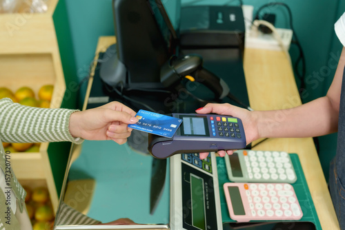 Credit card being handed over to payment terminal during transaction at fruit store modern cashless purchase concept small business customer and vendor exchanging contactless payment inside grocery