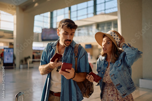 Papier peint Worried couple checking flight schedule on smart phone at airport
