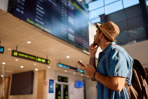 Papier peint Male traveler checking his flight schedule at airport terminal.