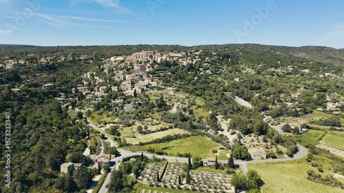 Traditional Provencal village Gordes surrounded by cultivated fields and low rolling hills, aerial view