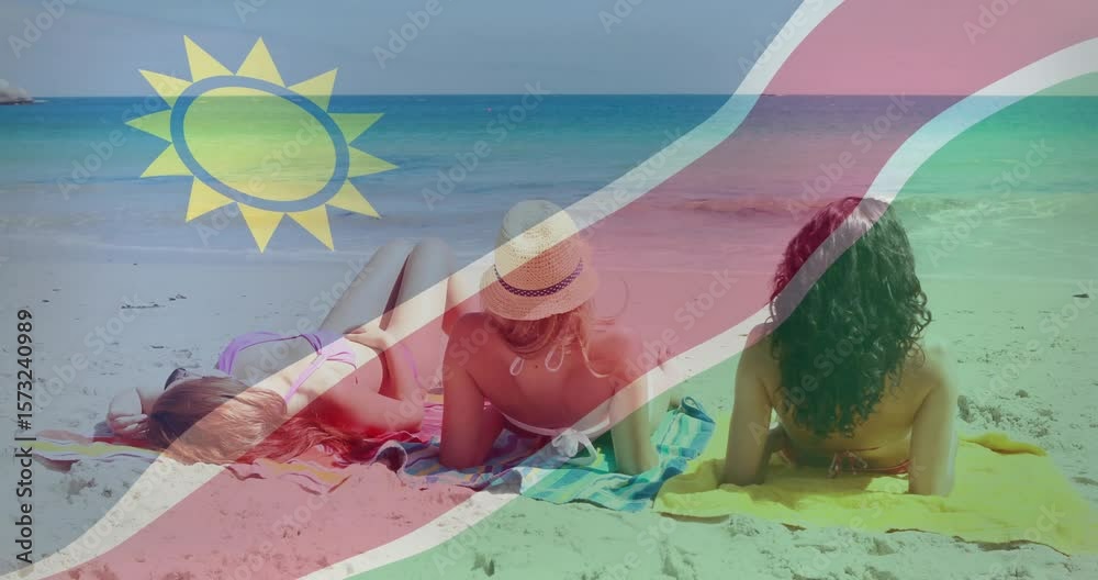 travelers sunbathing on beach towels as Namibian flag rippling in waving across horizon for rest