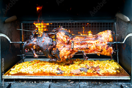 Whole pig spit roasted. Pig roasted on a barbecue spit. Outdoor Barbecue grill in open bbq pit. The little pig is roasted whole on an open fire. Outdoor piglet grilling. Pork meat garden barbecue. 