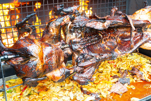 Whole pig spit roasted. Pig roasted on a barbecue spit. Outdoor Barbecue grill in open bbq pit. The little pig is roasted whole on an open fire. Outdoor piglet grilling. Pork meat garden barbecue. 