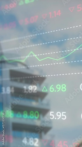Animation of multicolored trading board over low angle view of modern buildings against cloudy sky