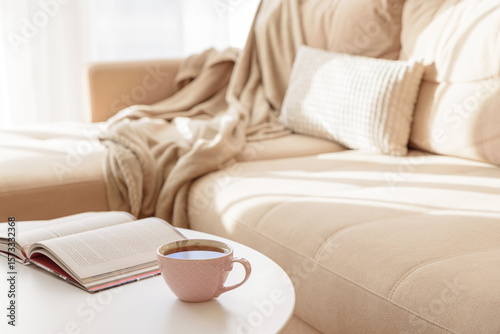 Cozy living room with a book and tea on a beige couch. Soft focus