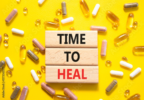 Medicine symbol. Concept words Time to Heal on wooden blocks. Beautiful yellow background with pills. Medicine concept and Time to Heal. Copy space