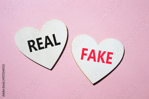 Real or Fake symbol. Concept word Real or Fake on wooden hearts. Beautiful pink background. Business and Real or Fake concept. Copy space
