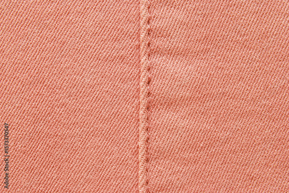 Fototapeta premium Pink cotton twill texture, a detail of seamed pink pants with a stitch in the center 