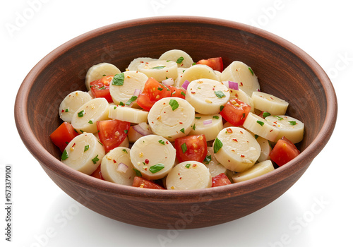 Heart of palm salad with tomatoes and herbs in a brown ceramic bowl, close up studio shot