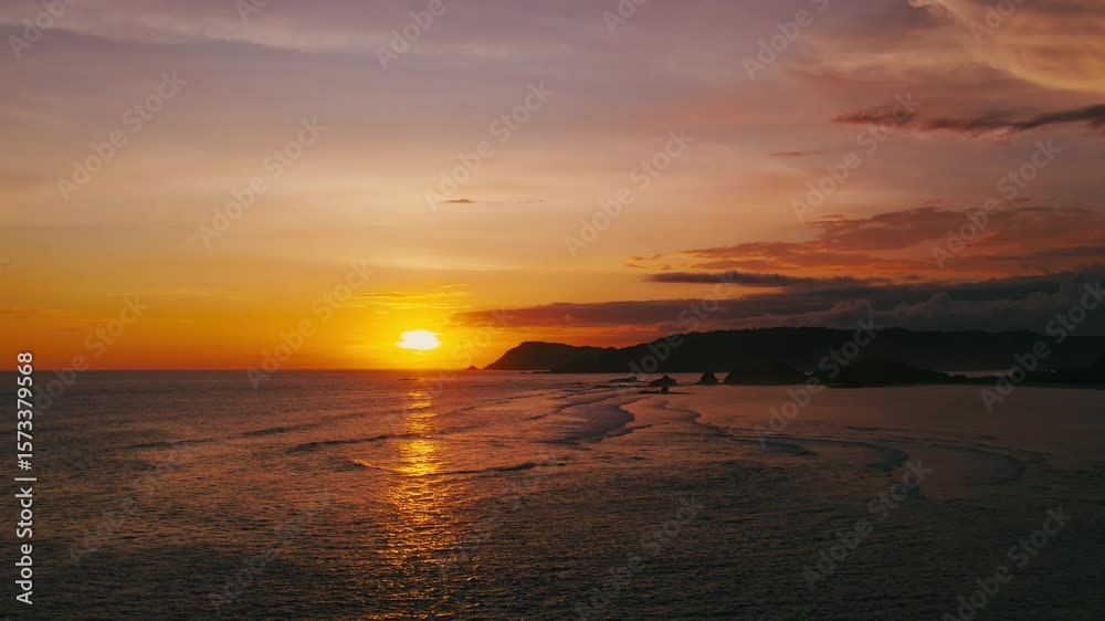 A stunning sunset casts golden hues over calm ocean waves lapping the sandy shore, with rolling coastal hills in the background, creating a perfect setting to appreciate natures beauty A stunning sunset casts golden hues over calm ocean waves lapping the sandy shore, with rolling coastal hills in the background, creating a perfect setting to appreciate natures beauty