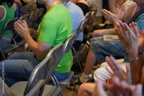 Fotografia A diverse audience seated on folding chairs claps in applause
