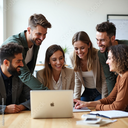 A diverse group of business professionals gathers around a laptop in a modern office, collaborating on a project and sharing ideas with enthusiasm and teamwork