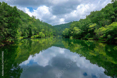 Serene Green Lake Surrounded by Lush Foliage and Reflecting Clouds in a Tranquil Natural Landscape