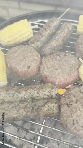 Vertical video social media - Closeup slow pan shot of burgers, kebabs, and cobs of sweetcorn cooking on a grate over hot flaming charcoal in an outdoor barbecue grill.