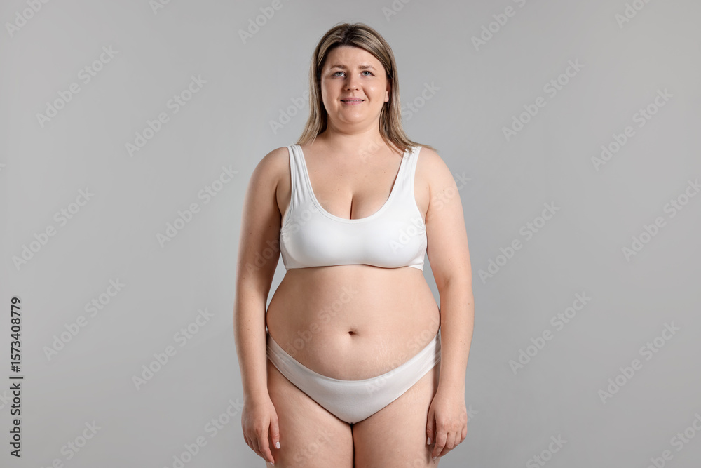 Fototapeta premium Weight loss. Plus size woman in underwear on gray background